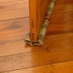 A double draft stopper made from fabric slides under a wooden door and moves with the door when it is opened