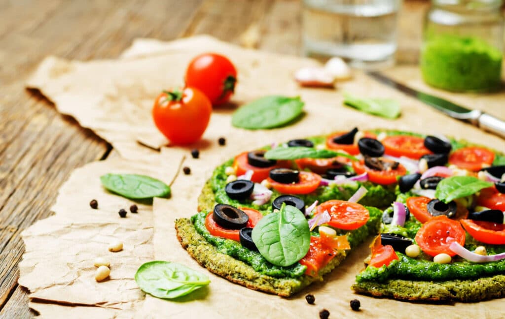 zucchini crust pizza with tomatoes, spinach, and olives