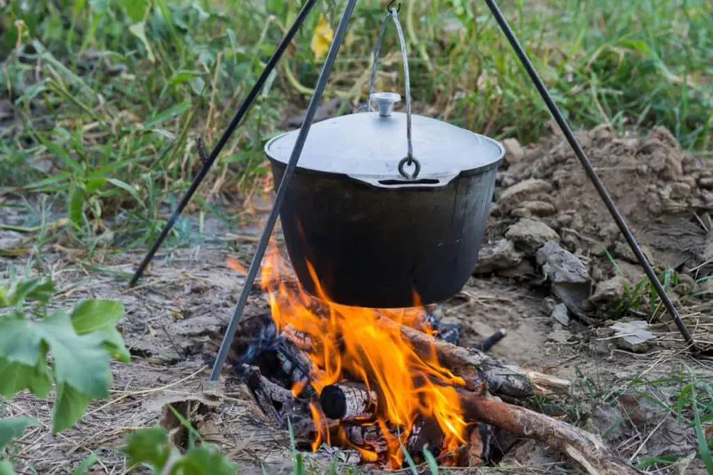 black pot of covered stone soup over an open fire 