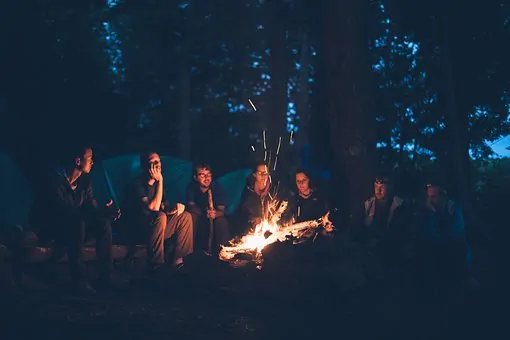 friends sitting around the campfire cooking food