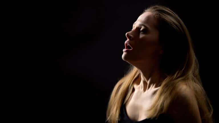 woman with mouth gasping for air in front of black background