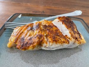 cooked fish with seasoning on a plate with a fork
