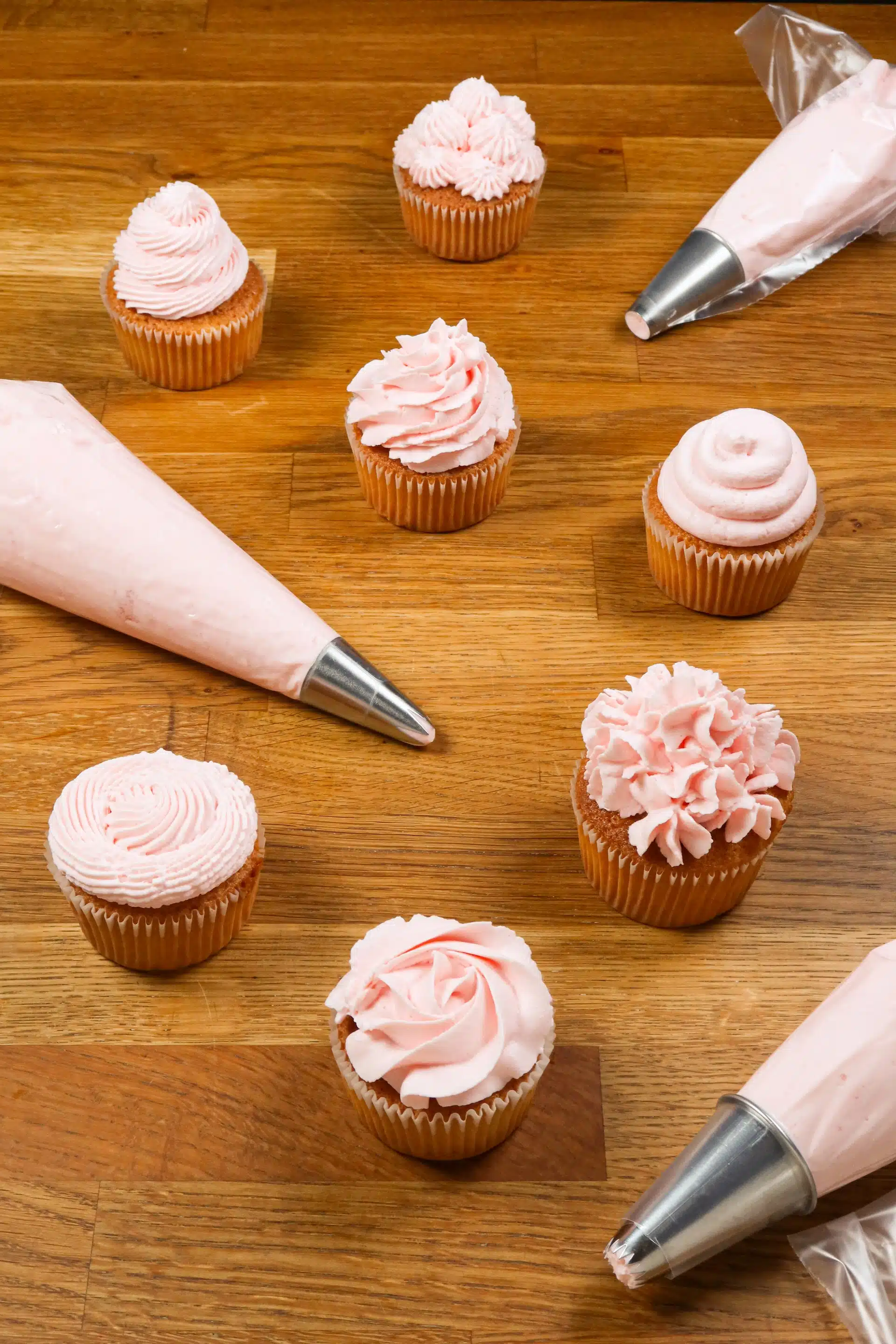 pink frosted cupcakes and frosting bags with tips