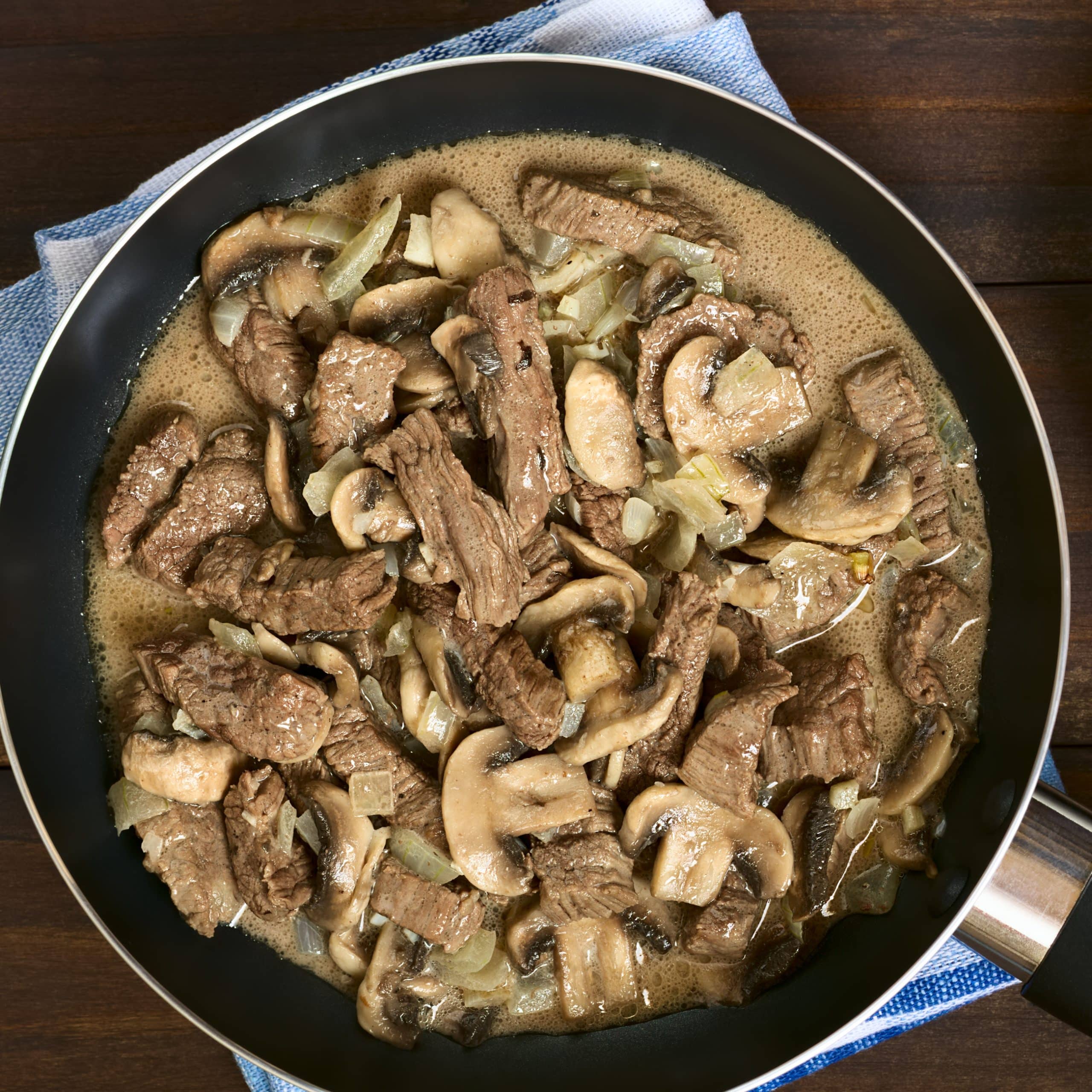 Beef Stroganoff in frying pan, a dish made of pieces of beef, mushroom and onion in cream sauce
