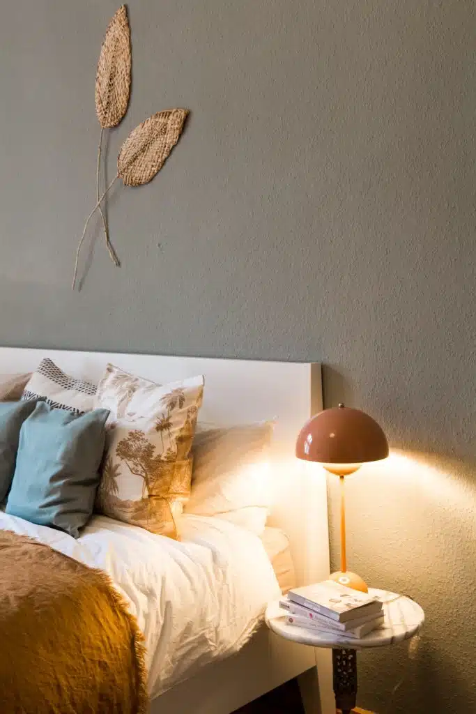 lamp beside bed with blue and cream pillows