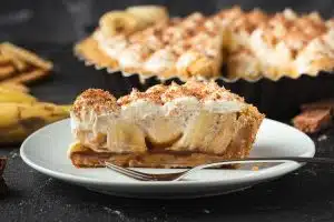 banana cream pie on white plate with silver fork