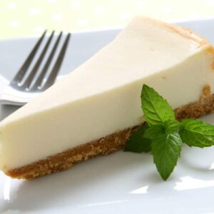 slice of no-bake cheesecake with basil garnish on white plate