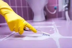 hack for cleaning grout using toothbrush and yellow gloves