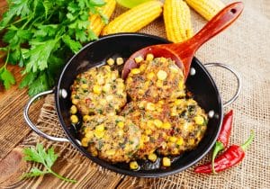 pork fritters in black frying pan with red spoon