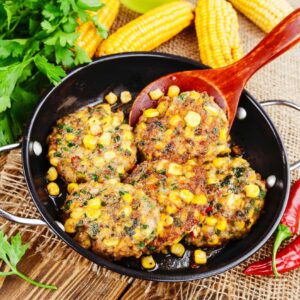 pork fritters in black frying pan with red spoon