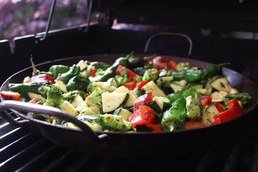 green and red vegetables in a black stir-fry pan