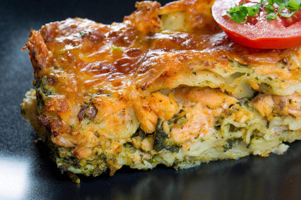 a serving of salmon lasagna with layers of noodles, salmon, and melted cheese on top