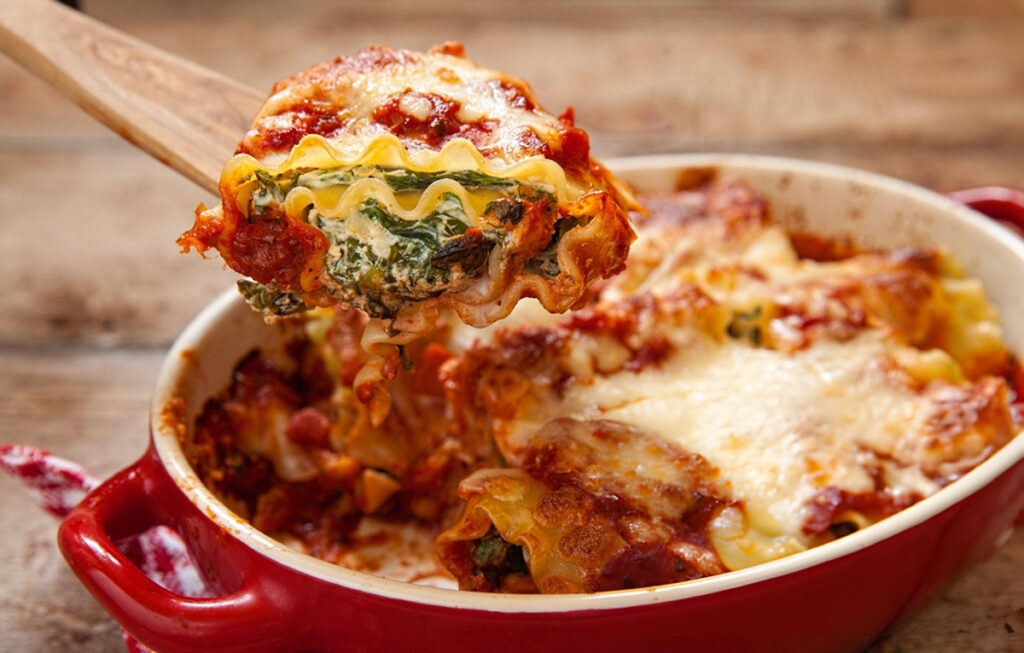 spinach lasagna with cheese and green spinach in red and white bowl