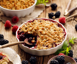 fruit crumble recipe in white ramekin with spoon scooping colorful berries