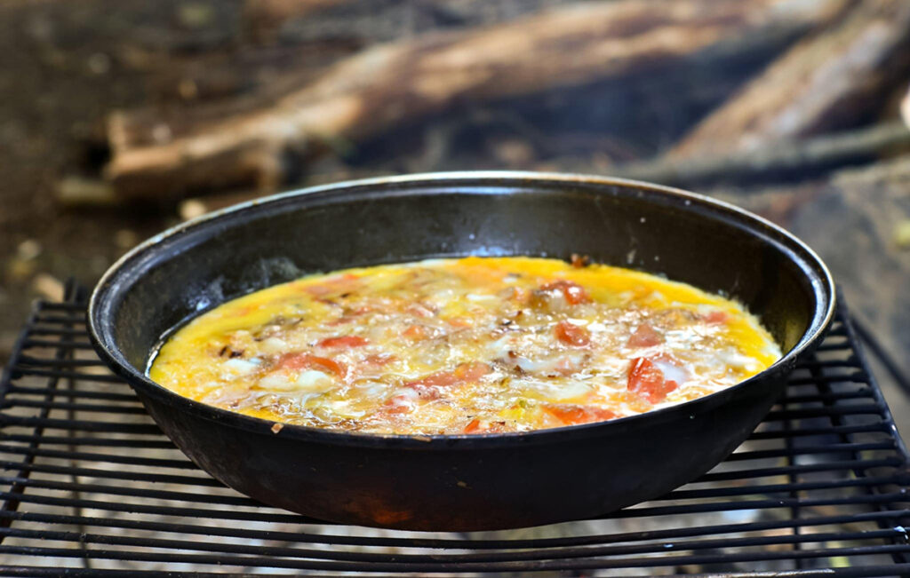 one skillet breakfast in black pan on grate over fire